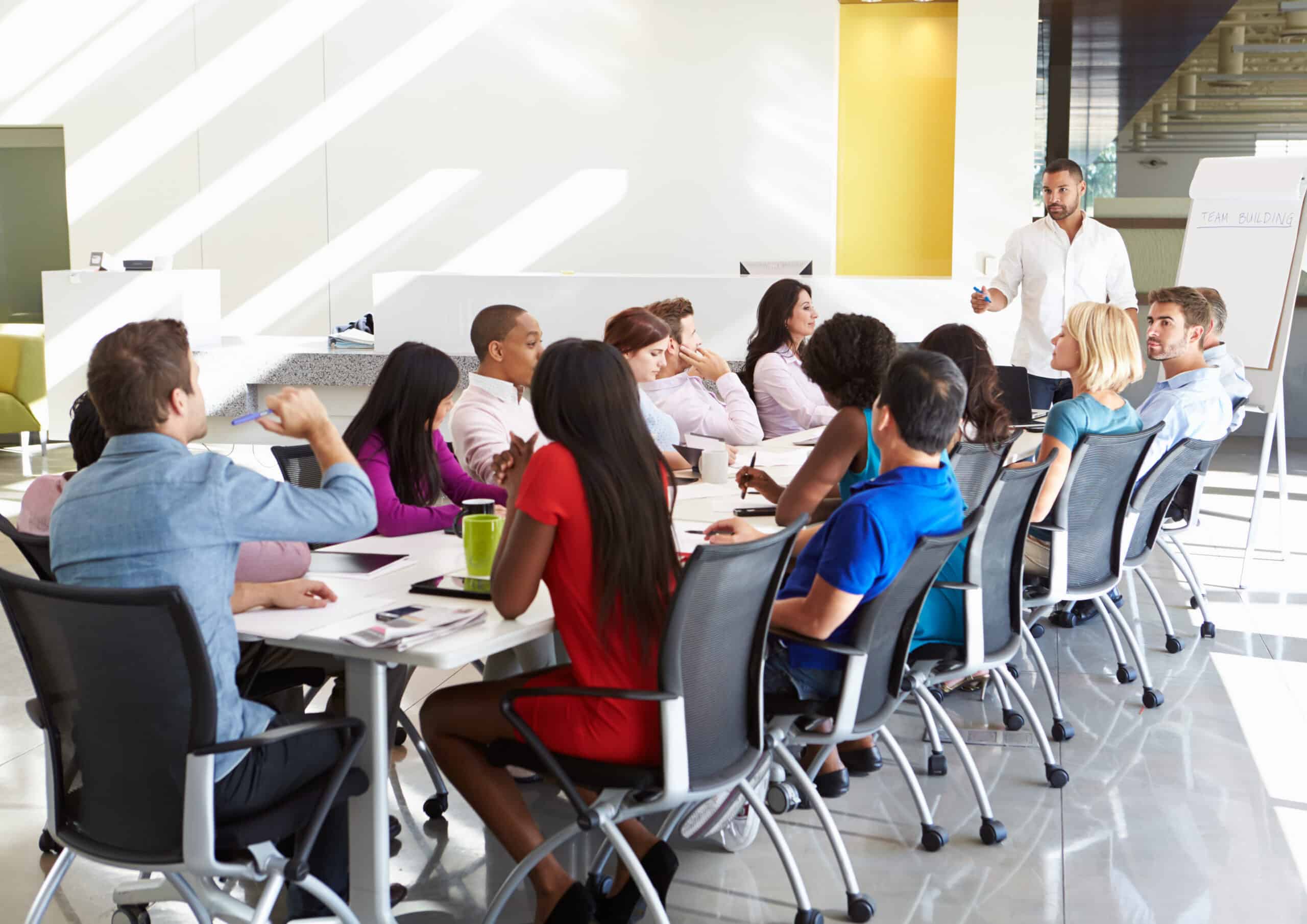 Businessman Addressing Meeting Around Boardroom Table